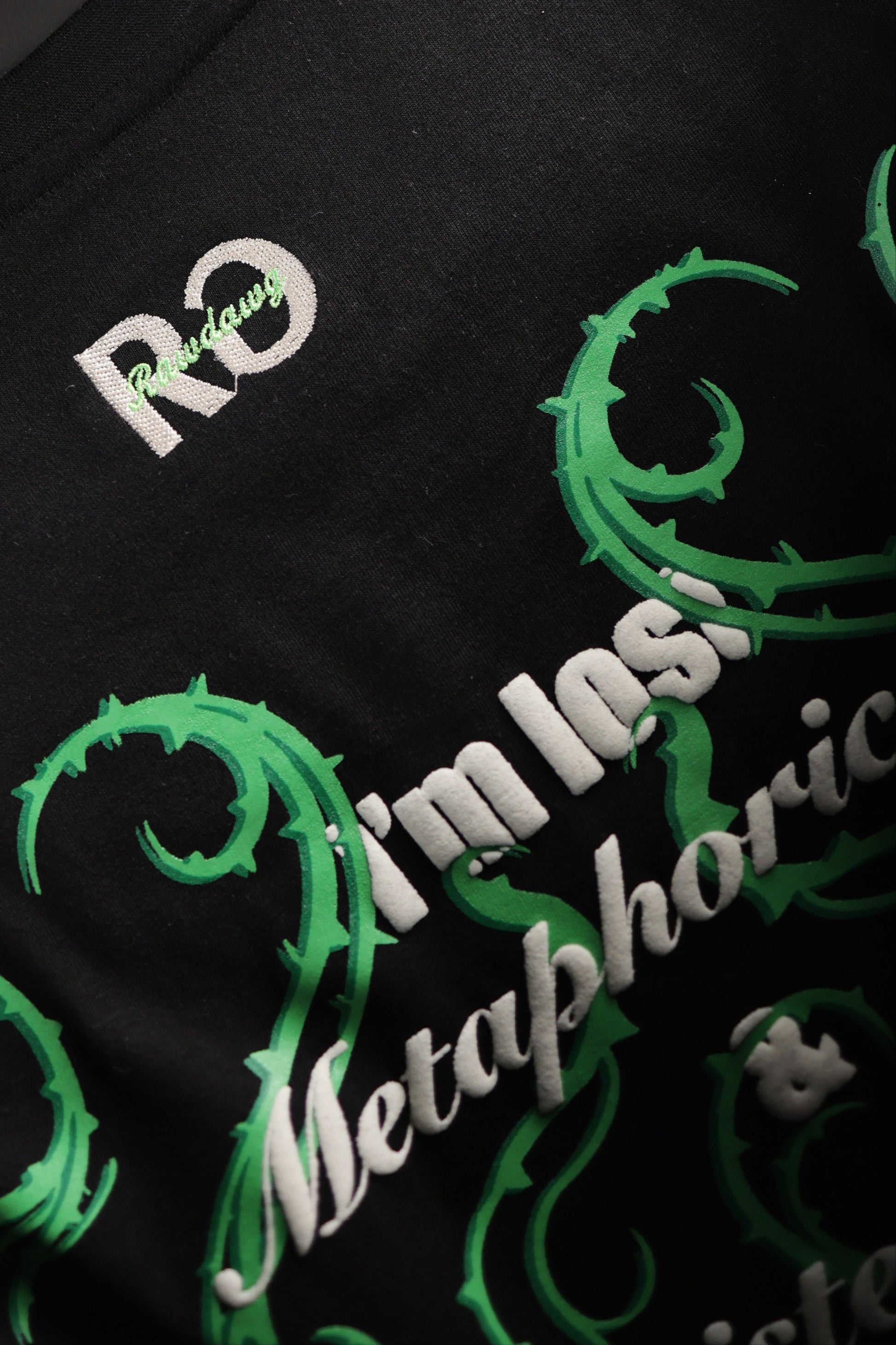 Black t-shirt with green and white text and graphics on a dark background